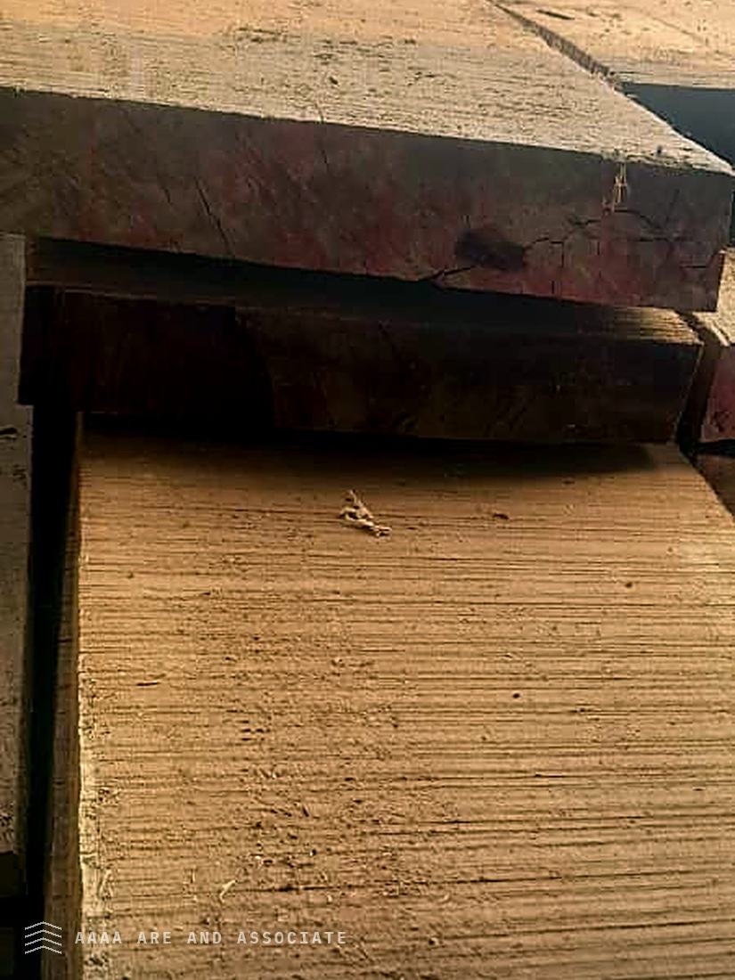 Close view of the freshly sawn face and end grain of heavy hardwood baulks stacked at a Nigerian conversion yard